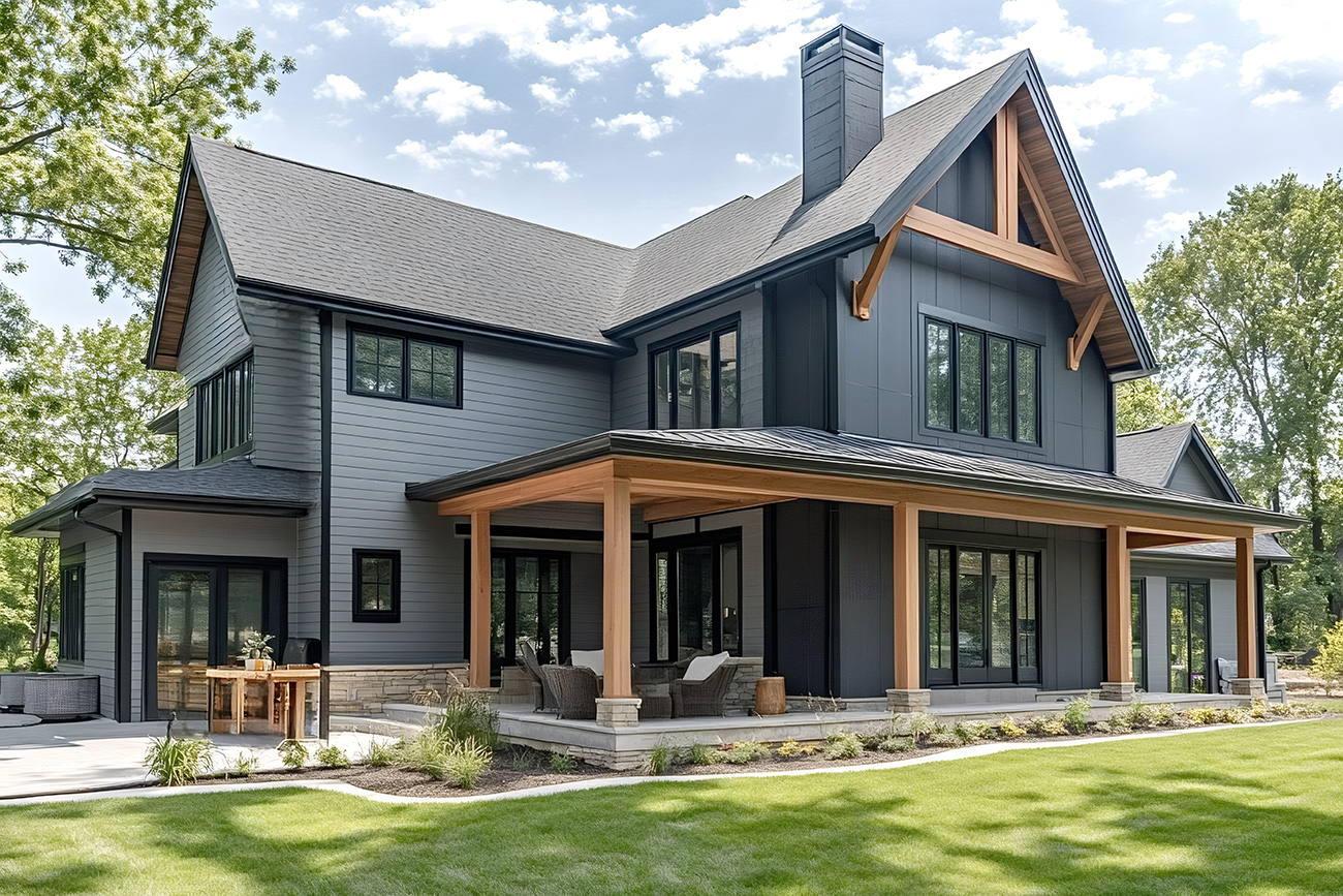 Modern farmhouse showcasing a blend of contemporary and rustic elements, featuring a welcoming covered patio, dark gray siding, and expansive windows creating a seamless connection with nature